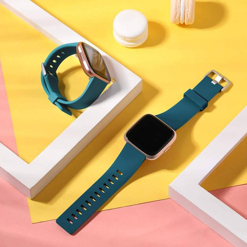 Two Fitbit Versas with Teal Blue Green Bands on Display.