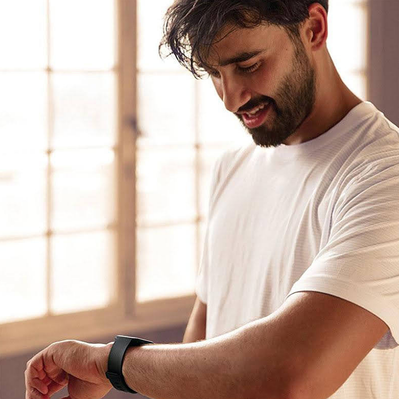 Male Model Smiling and Checking his Versa Watch with a Black Silicone Sport Band.